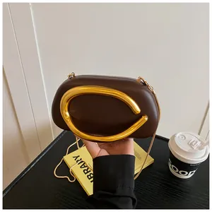 Detailed view of dark brown box clutch with oversized gold metal ring handle and chain