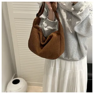 Detail of dark brown corduroy shoulder bag showing vertical texture and wide strap