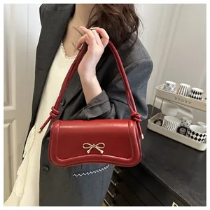 Detailed close-up of a red glossy leather handbag featuring a golden metal bow buckle