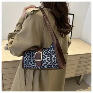 Dettaglio borsa a spalla leopardata con fibbia dorata indossata con trench coat beige