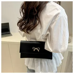 Detailansicht einer schwarzen Klapptasche mit goldener Schleife und Kettenriemen