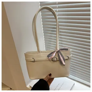 Dettaglio borsa tote crema con fibbia in metallo e nastro decorativo rosa a quadri