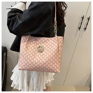 Détail du sac cabas rose avec motif 'M', logo doré et anse ornée d'une chaîne dorée