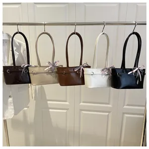 Detailed row of tote bags in five colors with decorative bow charms and belt buckles