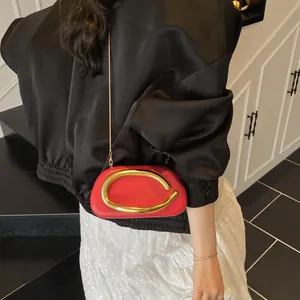 Red leather crossbody bag with gold C-shaped buckle and slim metal chain strap