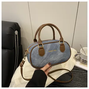 Detail of denim Boston bag with brown leather handles and adjustable shoulder strap