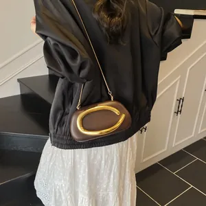 Brown leather crossbody bag with oversized golden horseshoe ring and metal chain strap