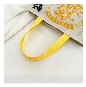 Close-up of durable yellow webbing strap attached to an ivory canvas drawstring bucket bag