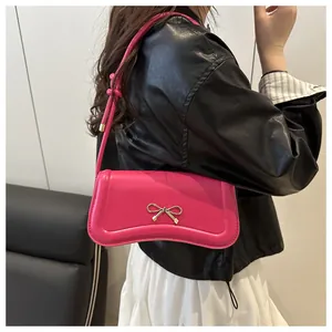 Close-up of pink crossbody bag with gold bow clasp and stylish knotted shoulder strap