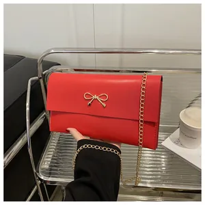 Nahaufnahme der roten Ledertasche mit goldener Schleife und feiner Metallkette