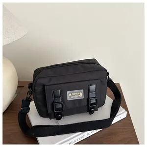 Détail d'un sac bandoulière en toile noire avec sangle réglable et boucles décoratives