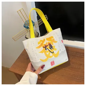 Detailed close-up of a white canvas bucket bag with yellow 'Fortune' calligraphy and handle