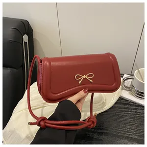 Detailed close-up of dark red rectangular handbag with elegant golden bow metal clasp