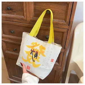 Detail of canvas bucket bag with yellow woven handle and Chinese calligraphy print