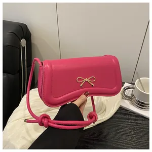 Close-up of rose pink PU leather handbag with gold bow clasp and knotted strap detail