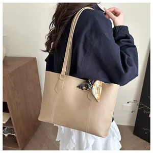 Detailed view of beige tote bag featuring white stitching and decorative silk scarf handle