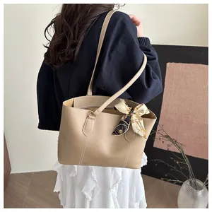 Detail of khaki tote bag featuring white contrast stitching and a silk scarf handle wrap