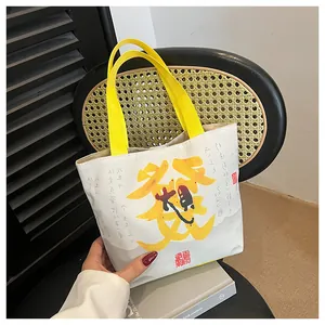 Close-up of cream canvas tote bag with yellow straps and Chinese calligraphy artwork