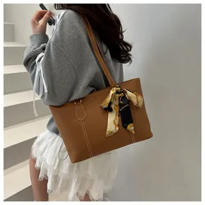 Detail of a brown PU leather tote bag featuring contrast stitching and a decorative silk scarf