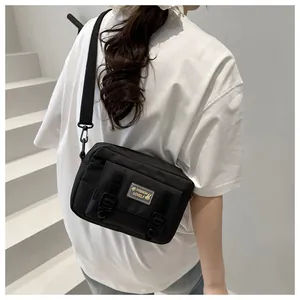Detail van de zwarte nylon crossbodytas met gespbanden en merklogo op de voorkant