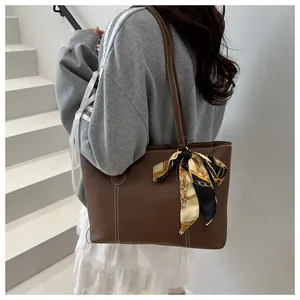 Detail of coffee brown tote bag with contrast white stitching and silk scarf accessory