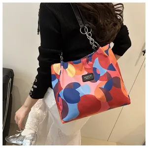 Detail of colorful geometric dot print tote bag with chain strap worn by a model