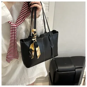 Close-up of black tote bag with white stitching and decorative printed silk scarf detail
