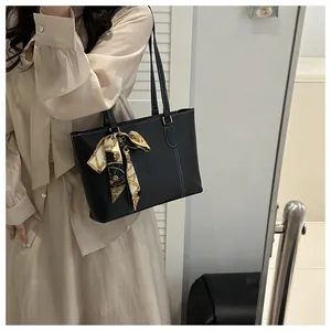Detail of black tote bag with white contrast stitching and a patterned silk scarf handle