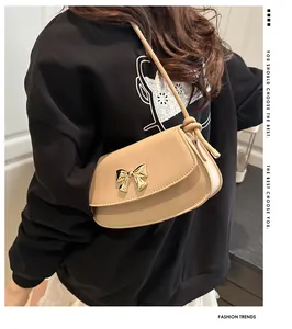 Détail du sac beige avec fermoir nœud doré et bandoulière à nœud élégant