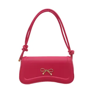 Chic magenta leather underarm bag featuring a gold bow buckle and unique curved base