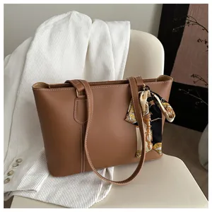Detail of brown faux leather tote bag with white contrast stitching and silk scarf