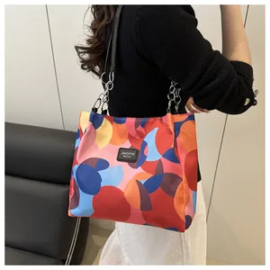 Close-up of abstract geometric tote bag with colorful patches and metal chain strap