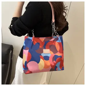 Detail of colorful geometric print tote bag featuring leather straps and metal chains
