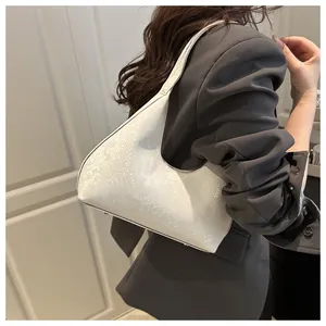 Detail of off-white snake-textured hobo bag worn by a model in a charcoal grey suit