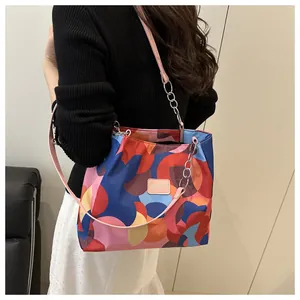 Detail of colorful geometric pattern tote bag with pink leather logo and metal chain