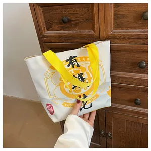 Detail of canvas bucket bag with yellow handle and Chinese calligraphy on wood background