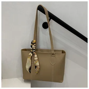 Detail of khaki tote bag with white contrast stitching and decorative printed silk scarf