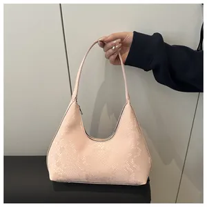 Detail shot of the pink snakeskin textured faux leather and crescent shape of the handbag
