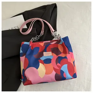 Close-up of geometric color-block tote bag with leather handles and silver chain detail
