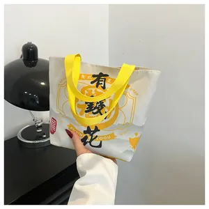 Detail of canvas bucket bag showing yellow straps and Chinese calligraphy lettering
