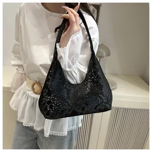 Detail of black snake-embossed faux leather hobo bag with sleek metallic zipper and scales