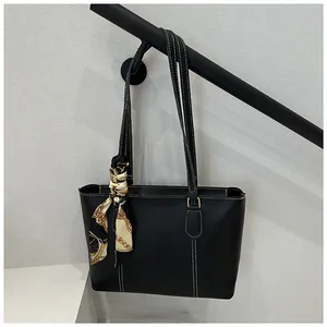 Detail of black tote bag with white stitching and decorative printed silk scarf on handle