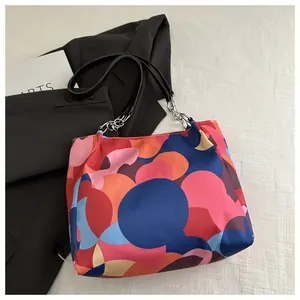 Detail of a large tote bag featuring colorful pop art patterns and silver chain handles