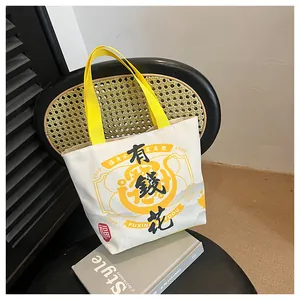 Close-up of cream canvas tote bag with black calligraphy and bright yellow handles