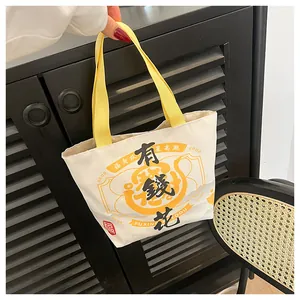 Detail of canvas tote bag with festive Chinese calligraphy and yellow handles