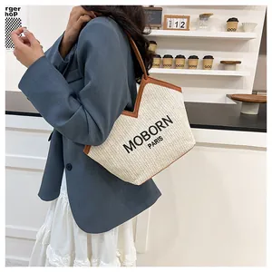 Detalle de bolso tote de paja tejida con bordado MOBORN PARIS y ribetes marrones