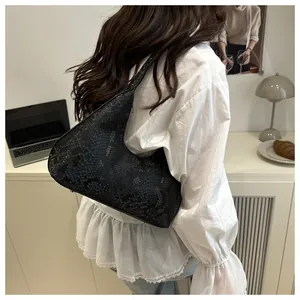 Close-up of black snakeskin textured hobo bag worn by a model in a minimalist setting