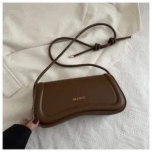 Close-up of dark brown leather hobo bag featuring gold XM & BAGS logo and elegant knot detail