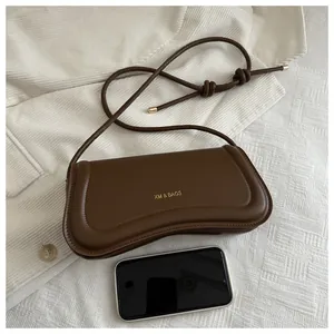 Top view of dark brown leather crossbody bag next to a smartphone for size reference