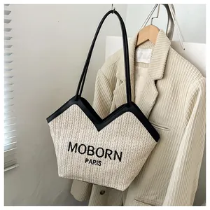 Detalle del bolso tote de paja MOBORN PARIS con ribetes de cuero sintético negro y bordado